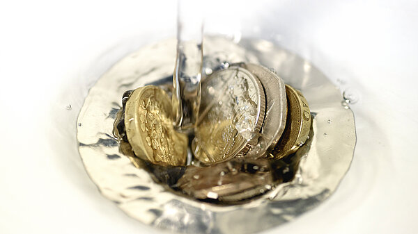 Pound coins going into a drain.