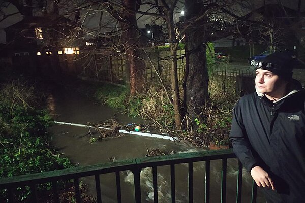 Cllr Will Frass kneeign beside a flood Fairywell Brook Cllr Shaun Ennis at a flooded section of Fairywell Brook on Wood Road
